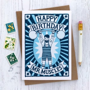 Pu&ograve; includere: Un biglietto di auguri di compleanno blu e bianco con un'illustrazione di un uomo che solleva pesi. Il biglietto dice "Buon compleanno Mr. Muscles".