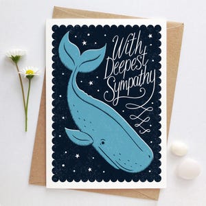 May include: A sympathy card with a blue whale illustration on a dark blue starry background. The card reads "With Deepest Sympathy" in elegant script. The card is on a brown envelope.