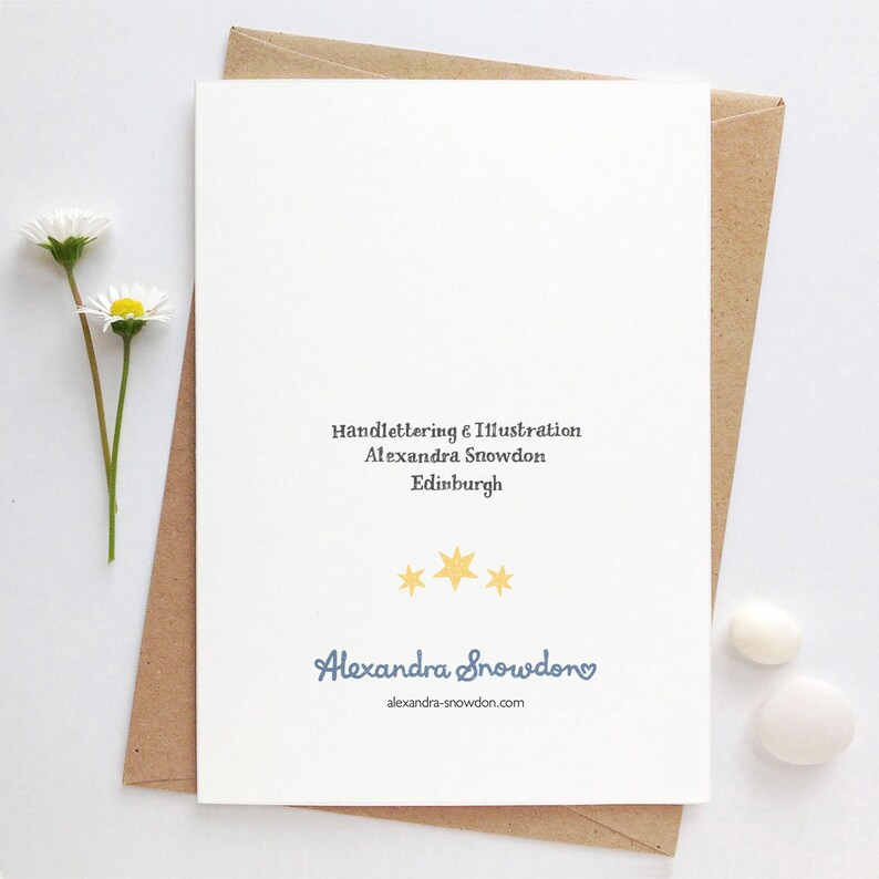 May include: A white card with blue text that reads "Handlettering & Illustration Alexandra Snowden Edinburgh" and "Alexandra Snowden alexandra-snowdon.com". There are three yellow stars above the name.