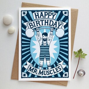 Pu&ograve; includere: Un biglietto di auguri di compleanno blu e bianco con un'illustrazione di un uomo che solleva pesi. Il biglietto dice "Buon compleanno Mr. Muscles".