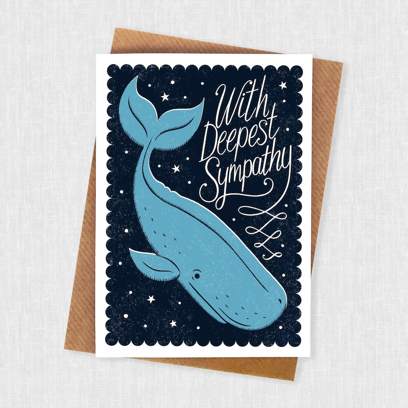 May include: A sympathy card with a blue whale illustration on a dark blue background with white stars. The card reads "With Deepest Sympathy" in elegant script. The card is set on a brown envelope.
