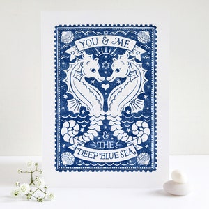 K&ouml;nnte beinhalten: Eine blaue und wei&szlig;e illustrierte Karte mit zwei Seepferdchen, die sich gegen&uuml;berstehen und ein Herz bilden. Der Text lautet "You & Me & The Deep Blue Sea".