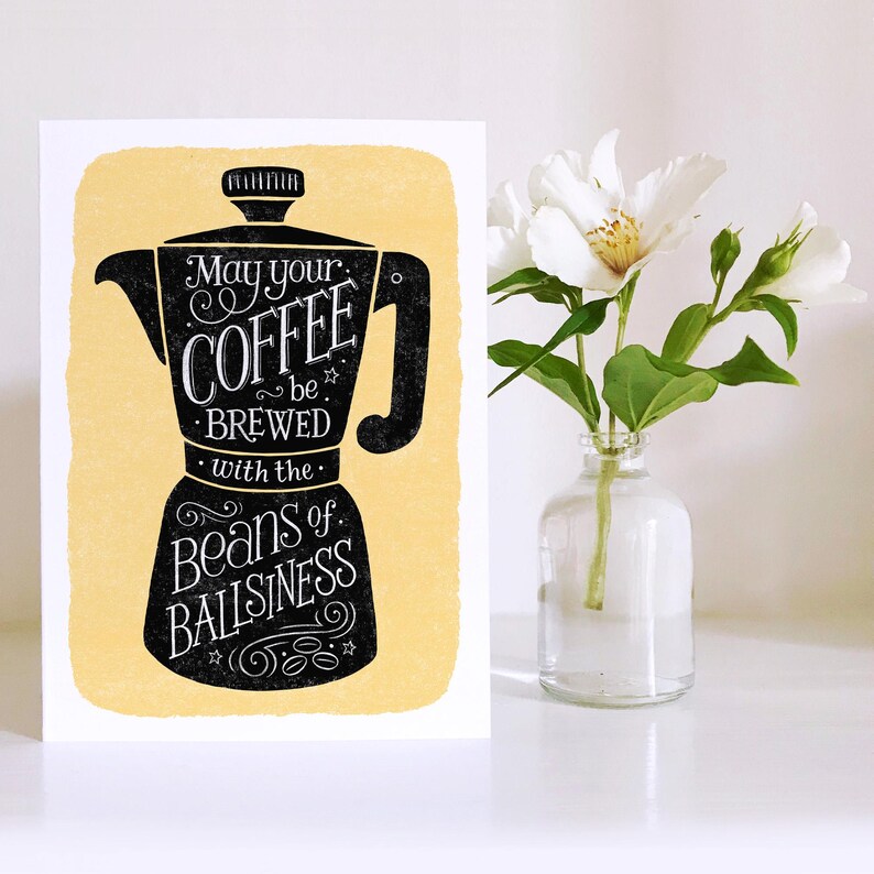May include: A yellow card with a black illustration of a coffee pot and the text "May your coffee be brewed with the beans of ballsinness".