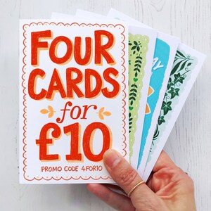 May include: Four greeting cards with a floral design for &pound;10. The cards are white with a red and orange handwritten text that says "Four Cards for &pound;10". The text also includes the promo code "4FOR10".
