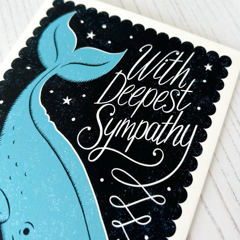 May include: A sympathy card with a light blue whale design on a black backdrop with white stars. The card displays the words "With Deepest Sympathy" in white script, set within a scalloped border.