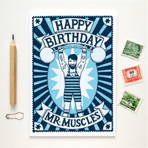 Pu&ograve; includere: Un biglietto d'auguri illustrato blu e bianco con un design in stile vintage. Il biglietto presenta un uomo che solleva pesi con il testo "Buon compleanno Mr. Muscles".