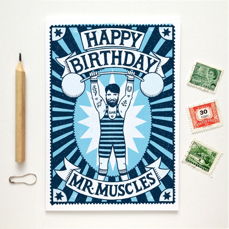 Pu&ograve; includere: Un biglietto d'auguri illustrato blu e bianco con un design in stile vintage. Il biglietto presenta un uomo che solleva pesi con il testo "Buon compleanno Mr. Muscles".
