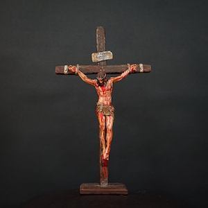 Könnte beinhalten: Ein Holzkruzifix mit einer Figur von Jesus Christus, in Rot und Weiß bemalt, die die Kreuzigungsszene darstellt.
