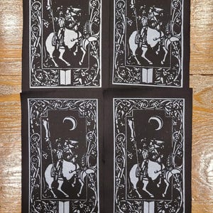 May include: Four black and white patches featuring a medieval knight on horseback. Each patch has a crescent moon, stars, and an ornate border. The knight holds a spear, and the design is reminiscent of a tarot card.