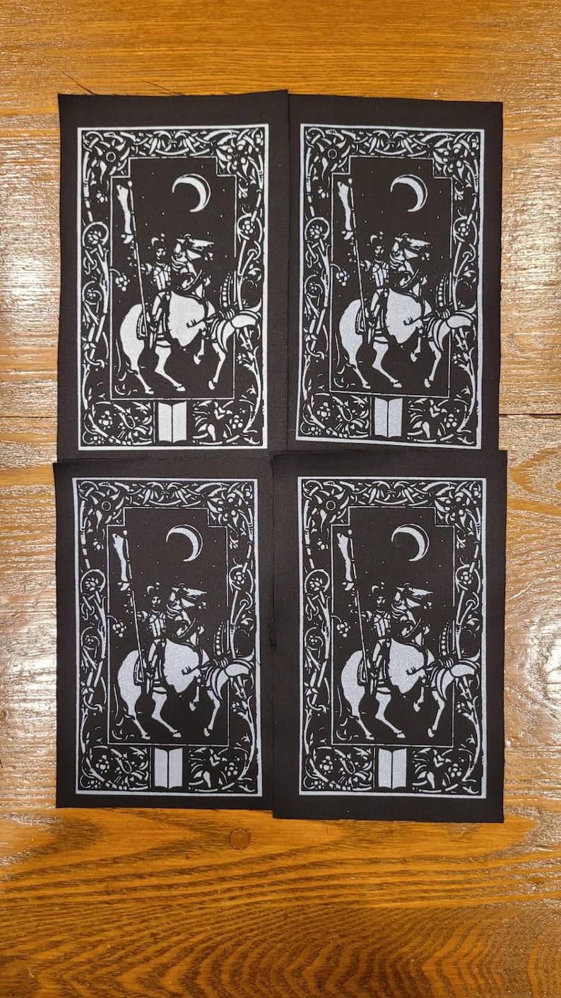 May include: Four black and white patches featuring a medieval knight on horseback. Each patch has a crescent moon, stars, and an ornate border. The knight holds a spear, and the design is reminiscent of a tarot card.