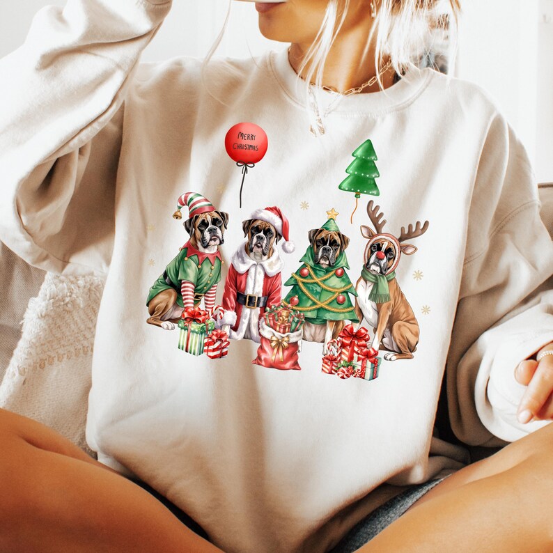 Pu&ograve; includere: Una felpa color crema con un design a tema natalizio. Raffigura quattro cani Boxer vestiti con abiti festivi: un elfo, Babbo Natale, un albero di Natale e una renna. Un palloncino rosso mostra le parole "Merry Christmas".