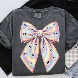 Pastel holographic bow PNG decorated with cute white ghosts. The bow features soft rainbow colors including pink, blue, yellow, and lavender. The design has a glossy shimmer effect, giving it a girly Halloween vibe. Ideal for sublimation and digital crafts.