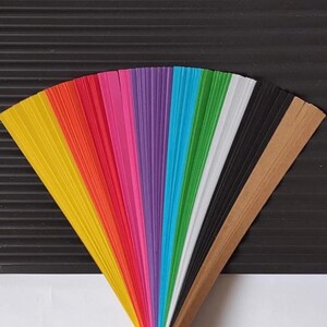10 Colors Quilling Paper Strips - High Quality 180 gsm Rainbow Palette Set DIY Kit, Typography & 3D Effect, Perfect Craft Supplies. Quilling paper strips in various widths, including 3mm, 5mm, 7mm, and 10mm. The paper is 180 GSM and comes in a pack of 100 strips. Best for - On-edge quilling, Lettering, Outline quilling and Structured designs'.The colors are black, brown, white, green, blue, purple, pink, red, orange, and yellow. The strips are arranged in a vertical row.