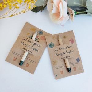 Op de afbeelding: Twee kraftpapieren zaadzakjes met potloden, met de tekst "Let love grow Henry & Sophia 31.08.2024". Bloemenillustraties en instructies zijn op de zakjes gedrukt. Een huwelijksbedankje.
