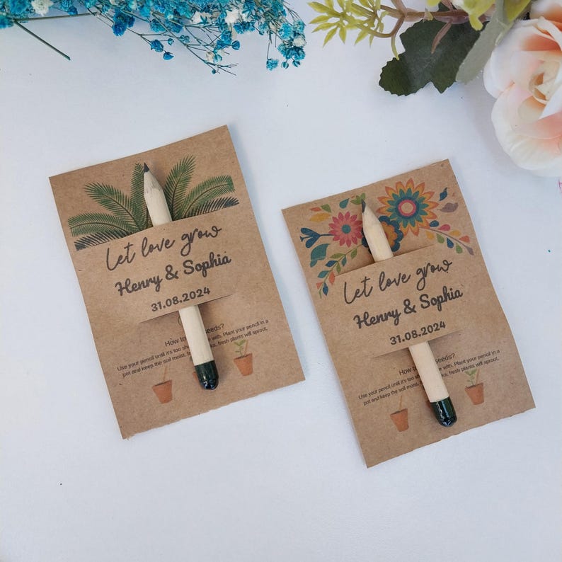 Op de afbeelding: Twee bruiloftbedankjes van kraftpapier met potloden. Elke kaart leest "Let love grow" met de namen "Henry & Sophia" en de datum "31.08.2024". E&eacute;n kaart heeft een palmboomontwerp, de andere een bloemenontwerp.
