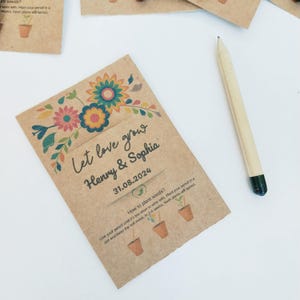 Op de afbeelding: Kraftpapieren zaadverpakking met bloemenontwerp en de tekst "Let love grow Henry & Sophia 31.08.2024". Inclusief een potlood met groene punt. De verpakking bevat instructies voor het planten van zaden.