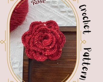 Peut inclure: Une rose rouge au crochet faite à la main avec des détails dorés. Le mot "Rose" est au-dessus de la fleur. Les mots "Crochet Pattern" sont écrits verticalement à droite. La rose est sur une surface en bois.
