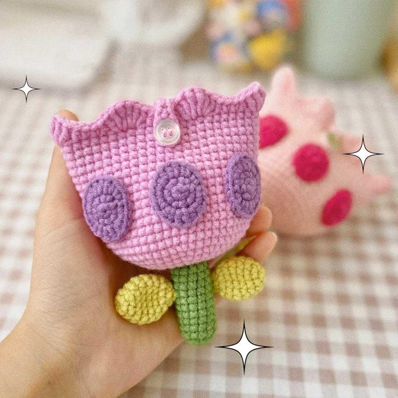 May include: A pink crocheted tulip with purple polka dots and a green stem. The tulip has a button on the front.