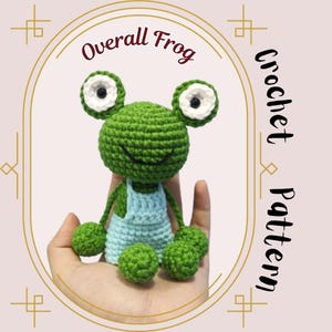May include: A handmade green crochet frog wearing light blue overalls. The frog has large white and black eyes and green limbs. The text "Overall Frog Crochet Pattern" is displayed in a decorative frame.