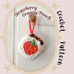May include: A handmade crochet strawberry granny pouch with a red strawberry design, white border, and brown top. The pouch hangs from a wooden knob with a red string. Text reads "Strawberry Granny Pouch" and "Crochet Pattern".