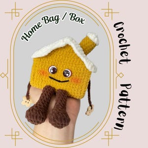 May include: Crochet pattern for a cute house-shaped bag or box. The house is yellow with a white roof and has a smiling face with brown eyes. The house has brown legs and is being held by a hand.