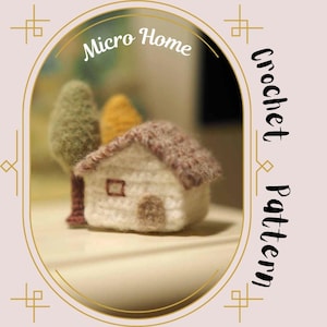 May include: A crocheted miniature house with a brown roof and a small tree next to it. The house is white with a brown door and window. The image is framed with a gold border and the text "Micro Home Crochet Pattern" is written in black on a white background.