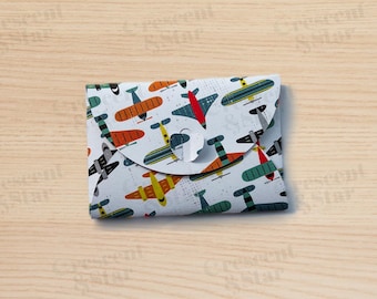 May include: A white envelope with a colorful pattern of airplanes. The envelope has a flap that folds over to close it.