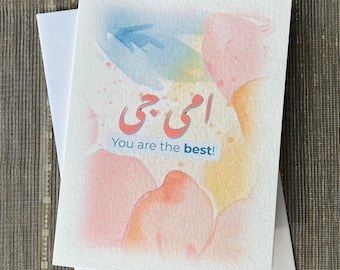 May include: A greeting card with a watercolor background in shades of pink, blue, and yellow. The card features the Arabic text "أنتِ الأفضل" which translates to "You are the best!" in English.