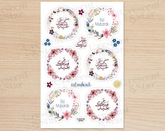 May include: A sheet of stickers with floral wreaths and the Arabic text "Eid Mubarak" in a calligraphy style. The stickers are perfect for adding a festive touch to gifts, cards, or home decor.