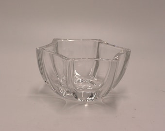 May include: A clear glass bowl with a star-shaped rim and a faceted design. The bowl is empty and has a slight curve to the sides.