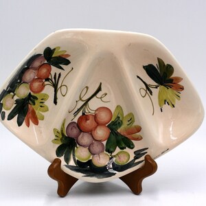 May include: A white ceramic serving dish with three sections, featuring a hand-painted design of grapes and leaves in shades of green, red, and purple.