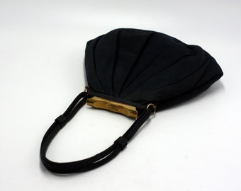 May include: A black fabric handbag with a pleated design and a gold clasp. The bag has a black strap.