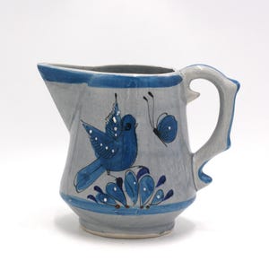 May include: A white ceramic mug with a black handle and the text "But First, Coffee" in a bold, black font. The mug is set against a neutral background, highlighting its simple design.