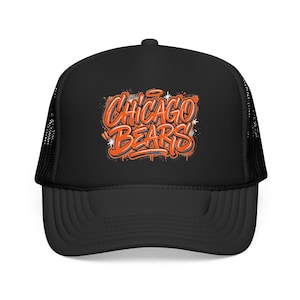 May include: A black trucker hat featuring a foam front panel and mesh back. The front displays graffiti-style text in orange and white that reads CHICAGO BEARS, accented with small star shapes and paint splatter effects against the black fabric.