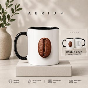 Pode incluir: Uma caneca de cerâmica branca com asa e interior pretos, apresentando um gráfico de um grão de café castanho na frente. O texto AERIUM aparece acima da caneca. Uma inserção mostra o design impresso em ambos os lados. Ícones indicam cerâmica premium, impressão de alta qualidade, lavável na máquina de lavar louça e segura para micro-ondas.