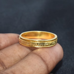 Peut inclure: Une bague en or avec une bande texturée. La bague est simple et élégante.