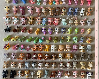 May include: A collection of small, colorful plastic animal figurines, including cats, dogs, and other creatures. The figurines are in various poses and colors, arranged in rows and columns. The collection includes a variety of animals.