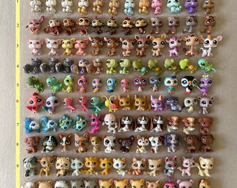 May include: A collection of small, colorful plastic animal figurines, including rabbits, monkeys, deer, turtles, birds, butterflies, dogs, cats, and other creatures. The toys are arranged in rows and columns on a neutral background.