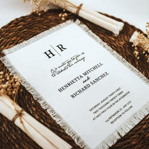 Puede incluir: Una invitaci&oacute;n de boda blanca con borde deshilachado, con las iniciales "HR" y el texto "We invite you to join us to celebrate our marriage Henrietta Mitchell and Richard Sanchez Saturday, August thirty-first Two thousand twenty three at half past four in the afternoon 123 Anywhere St., Any City Reception to follow"