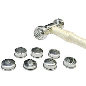 May include: A metal forming hammer with a wooden handle and a set of seven interchangeable metal forming heads. The hammer head has a checkered pattern. The forming heads have various textures and shapes.