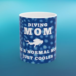 以下が含まれることがあります： 「DIVING MOM」の白い文字が大きく書かれた、青と白のセラミックマグカップ。 下にはダイバーの白いシルエットがあります。 マグカップには「...LIKE A NORMAL MOM JUST COOLER」と書かれています。