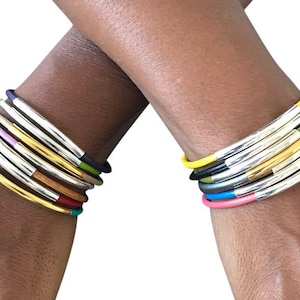 May include: A set of colorful leather bracelets with silver and gold accents. The bracelets are stacked on each other and are worn on both wrists.
