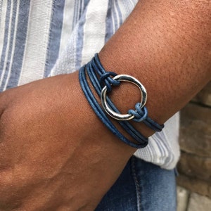 May include: A blue leather wrap bracelet with a silver circle charm.