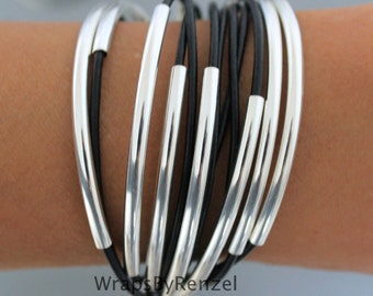 Pulsera multihebra de cuero negro con cuentas plateadas y cierre magnético.