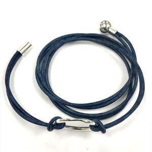 May include: A dark blue leather wrap bracelet with a silver ring and a silver bead at the end.