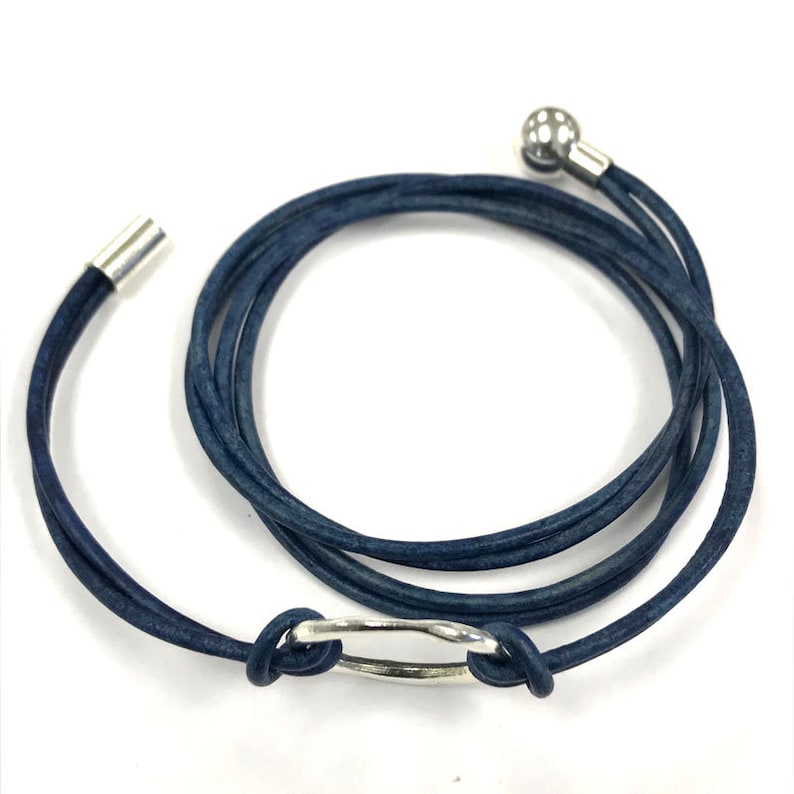 May include: A dark blue leather wrap bracelet with a silver ring and a silver bead at the end.