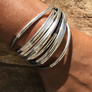 Pulsera de cuero gris con forma de tubo de plata y cierre magnético.