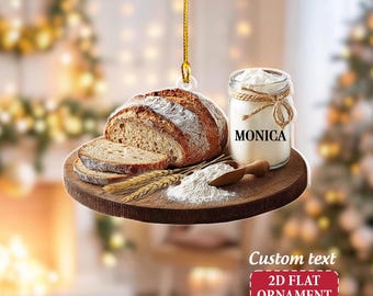May include: A 2D flat ornament featuring a loaf of sliced bread, flour, and a jar with the name "MONICA". The ornament includes a wooden scoop, wheat stalks, and a red banner that reads "Custom text 2D FLAT ORNAMENT".