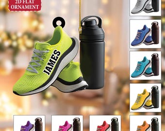 May include: A lime green 2D flat ornament featuring a pair of running shoes with the name "JAMES" printed on the side, paired with a black water bottle. Additional color variations of the ornament are displayed.