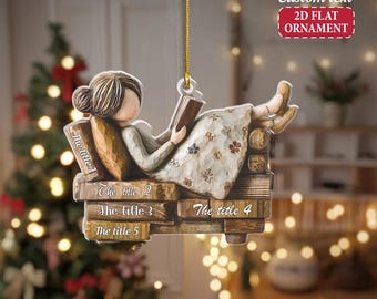 May include: A 2D flat ornament featuring a figure reading a book while reclining on a stack of books. The ornament has the text "The title 1", "The title 2", "The title 3", "The title 4", and "The title 5". The ornament is hanging from a gold string.